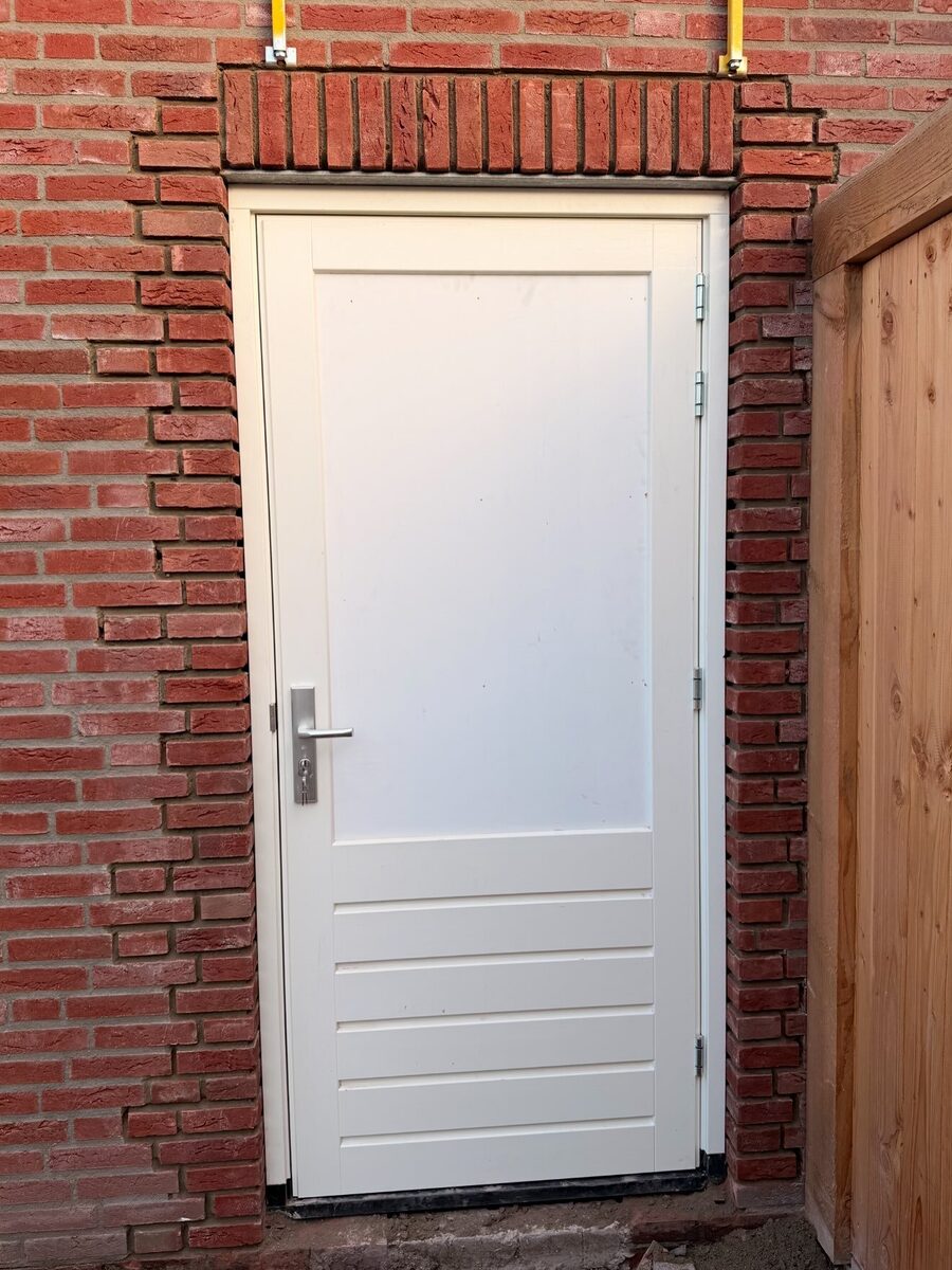 Na: de muur rond de deur is dichtgemetseld en gevoegd, met een rollaag boven het kozijn