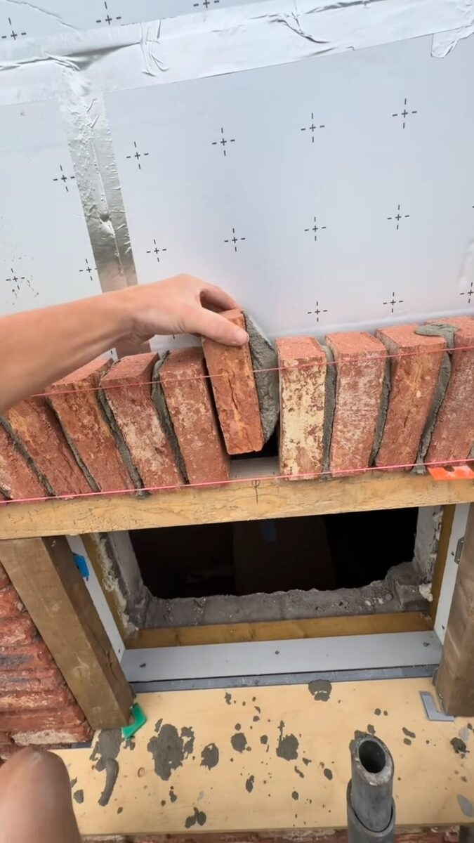 Stenen worden als rollaag op de latei boven een raamopening gezet, met isolatie erachter